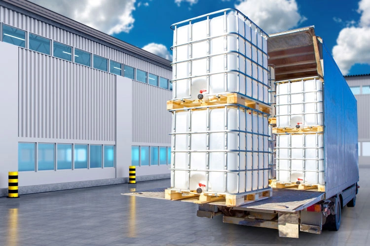 IBC chemical totes on pallets being loaded onto a delivery truck at a warehouse.